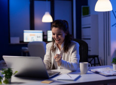 Business woman looking at professional laptop working at marketing graphs project late at night. Workaholic manager planning financial strategy using technology network wireless at company office