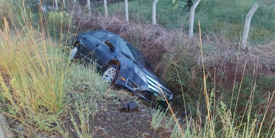 Veículo caiu em valeta após perder o controle na pista molhada; motorista saiu ileso.
